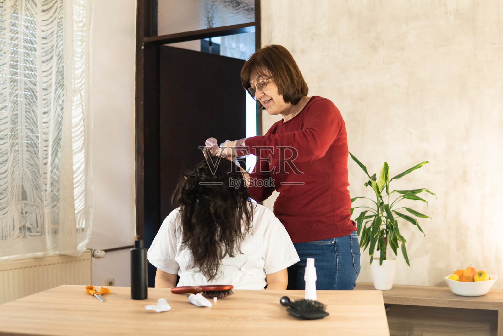 一位老年妇女在家给怀孕的女儿染头发。照片摄影图片