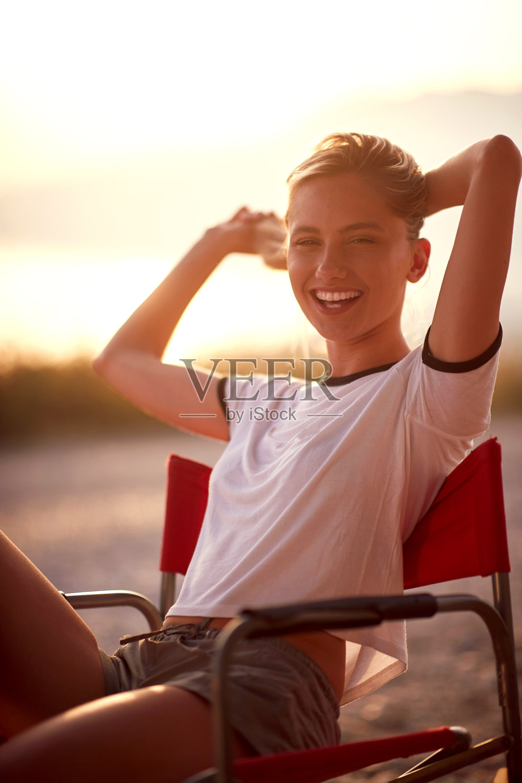 一个小女孩坐在野外的营地里摆姿势拍照。假期,野营的时候,自然照片摄影图片