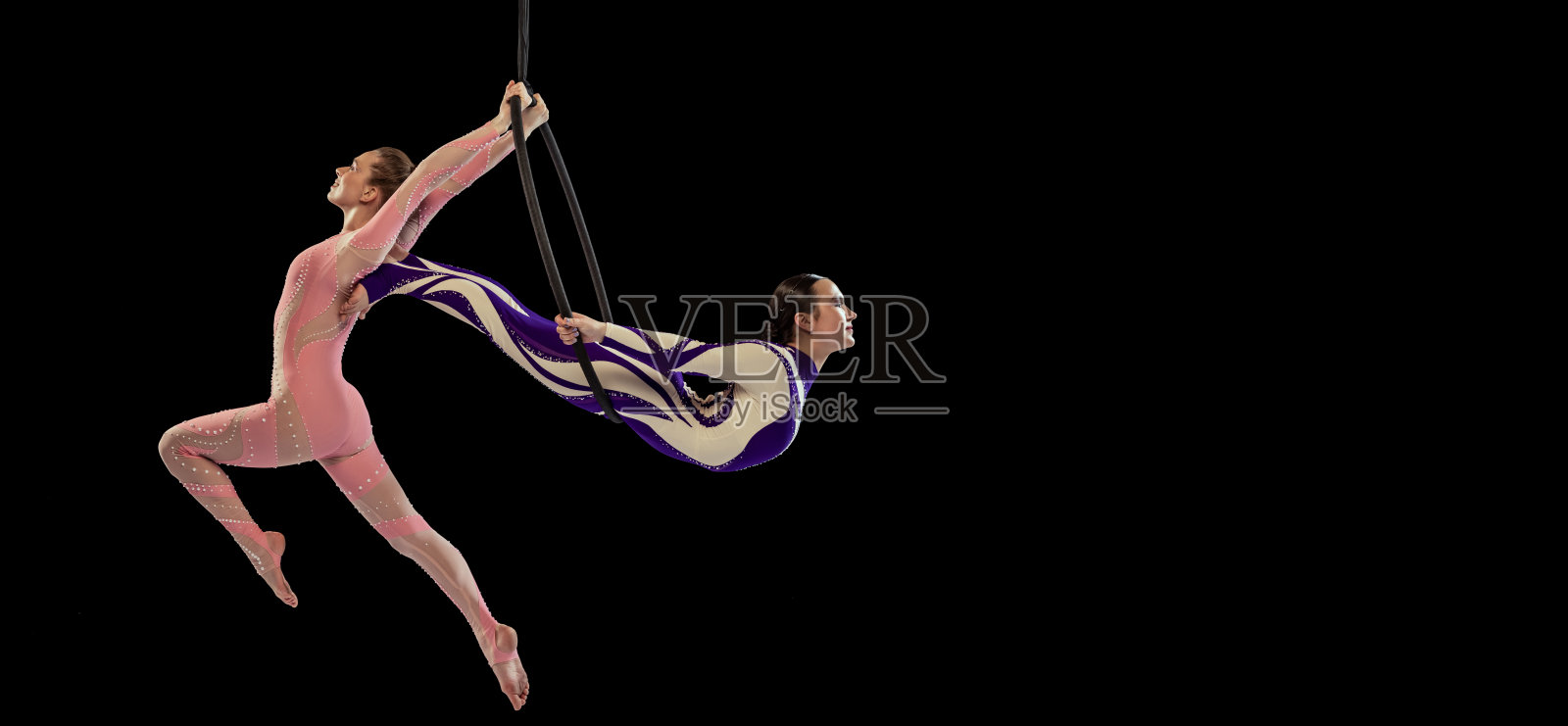 两个年轻女孩的肖像，专业的空中体操运动员表演的铁环孤立在黑色的工作室背景。摩天观景轮照片摄影图片