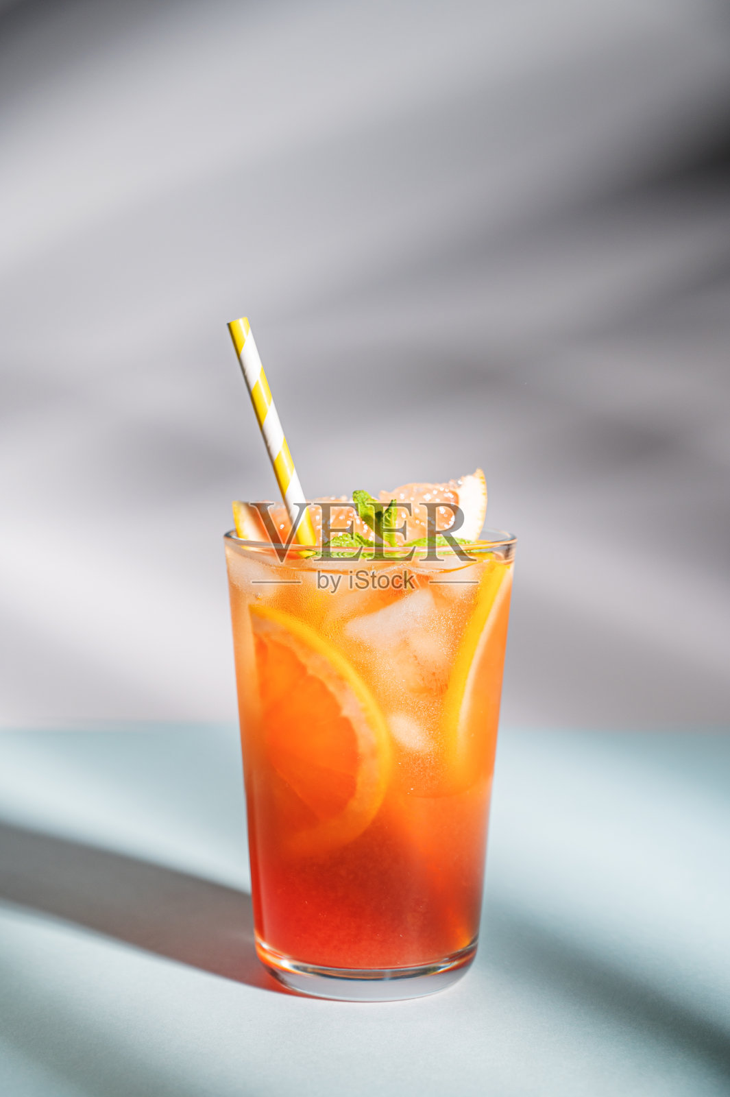 新鲜葡萄柚汁加冰，薄荷和葡萄柚片放入杯中，蓝色底色有阴影。前视图照片摄影图片