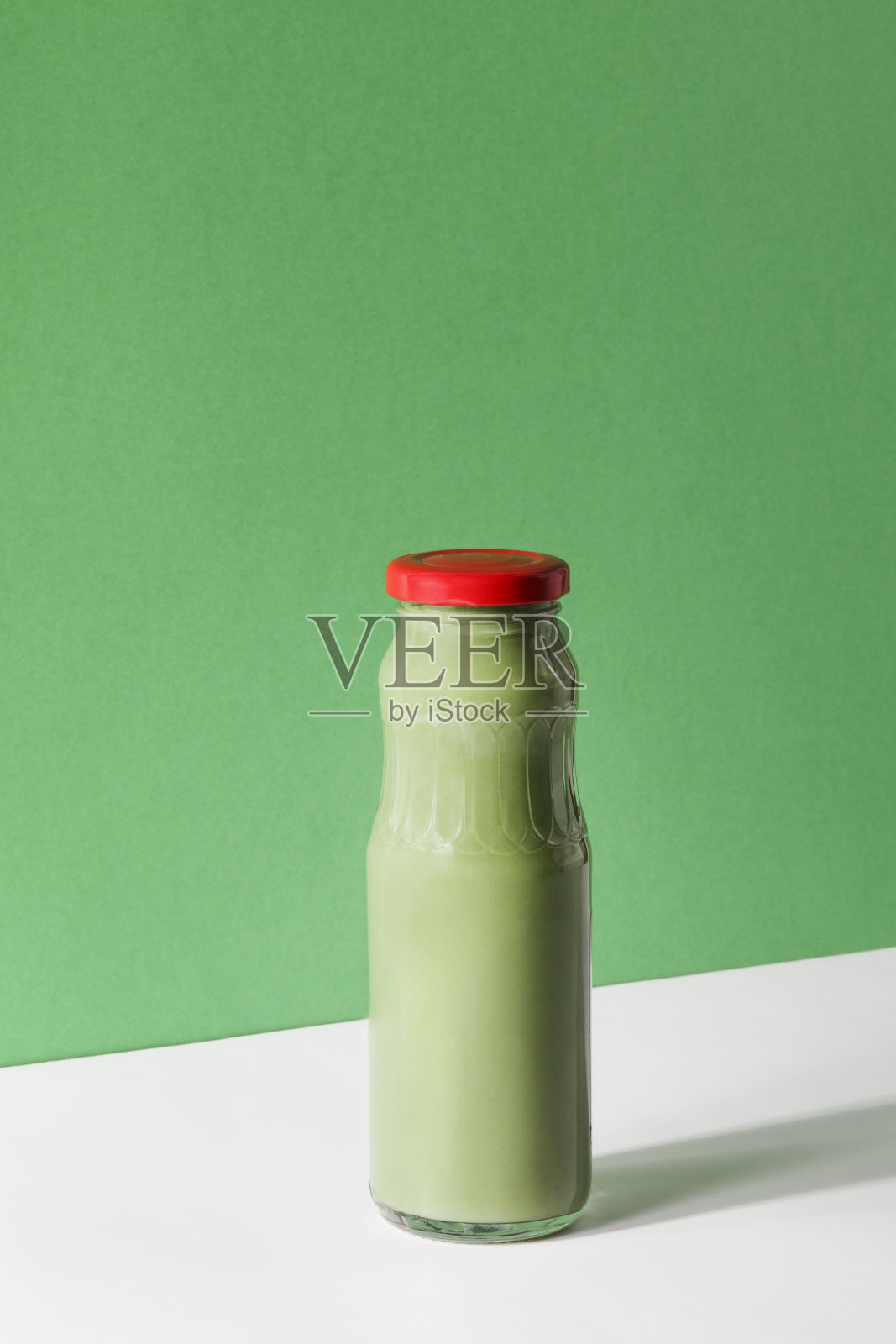 绿色奶昔在绿色和白色的背景，复制空间。素食食品的概念。健康饮食排毒食物办公室快餐。健康的早餐照片摄影图片