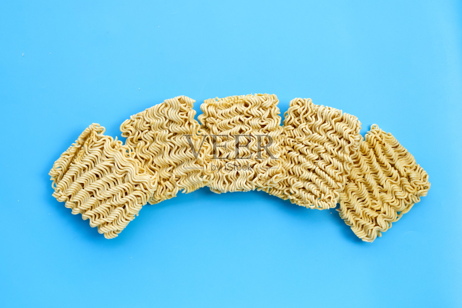 蓝色背景上的干方便面。照片摄影图片