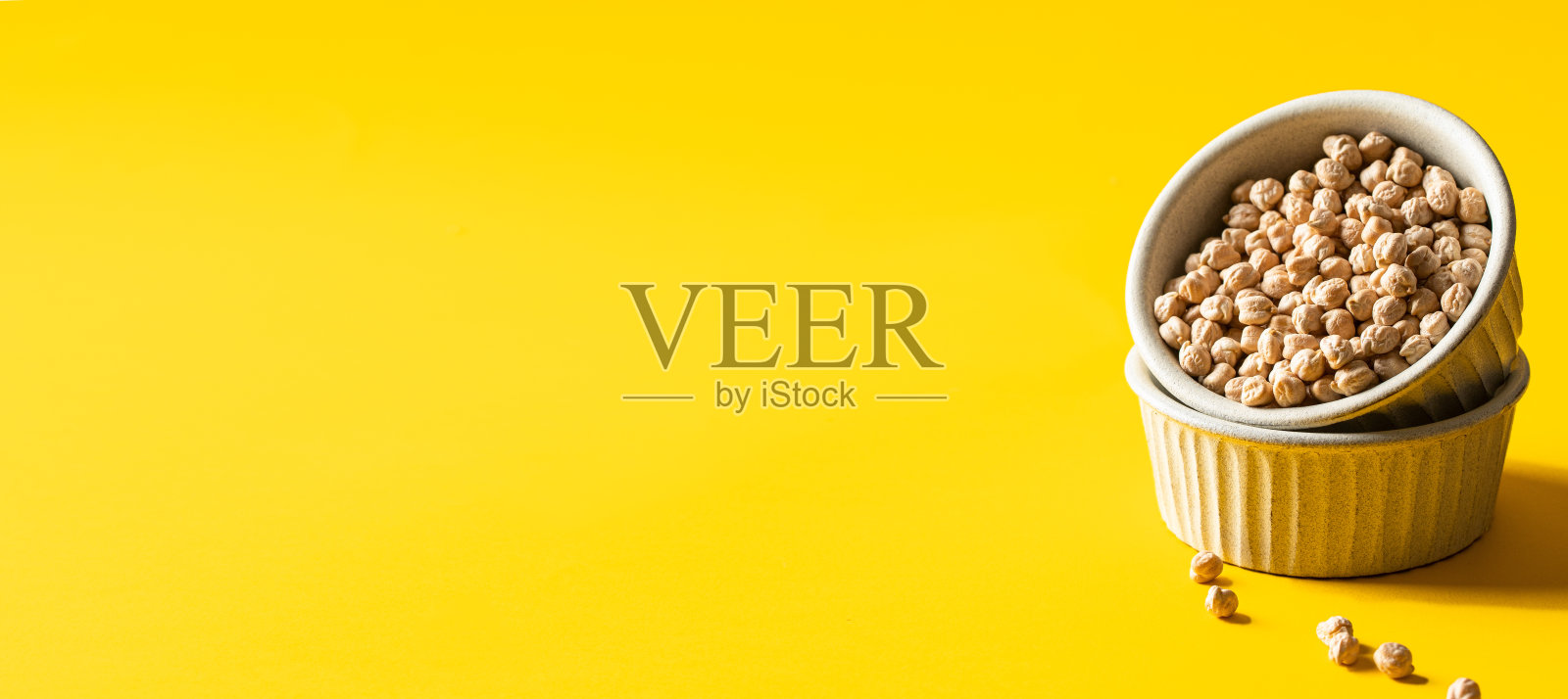 生鹰嘴豆在陶瓷碗上，大黄色背景为baqnner。副本的空间。照片摄影图片