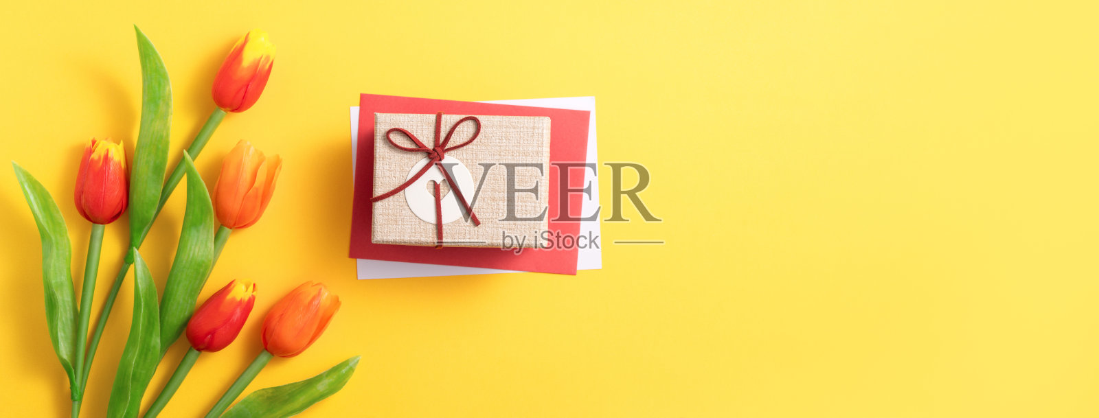 母亲节的背景。顶视图的礼物与郁金香花束在黄色的桌子背景照片摄影图片