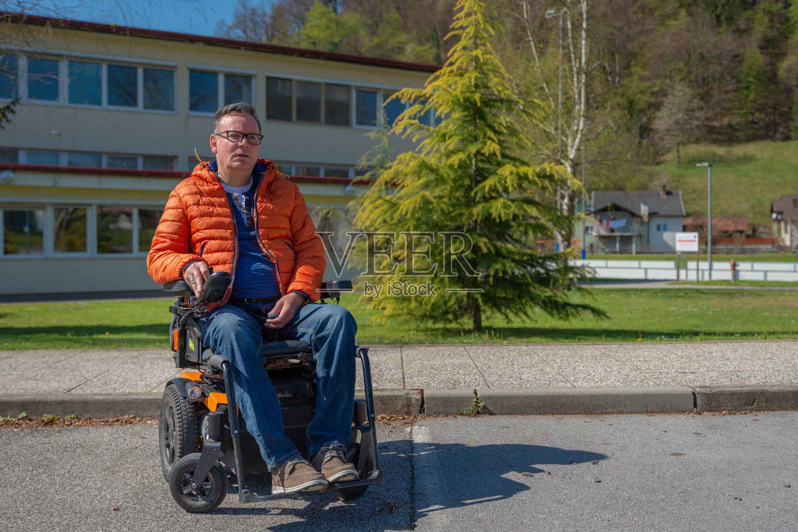 一名坐电动轮椅的残疾人乘坐电动电梯进入一辆面包车。在车的前面，在车上。照片摄影图片