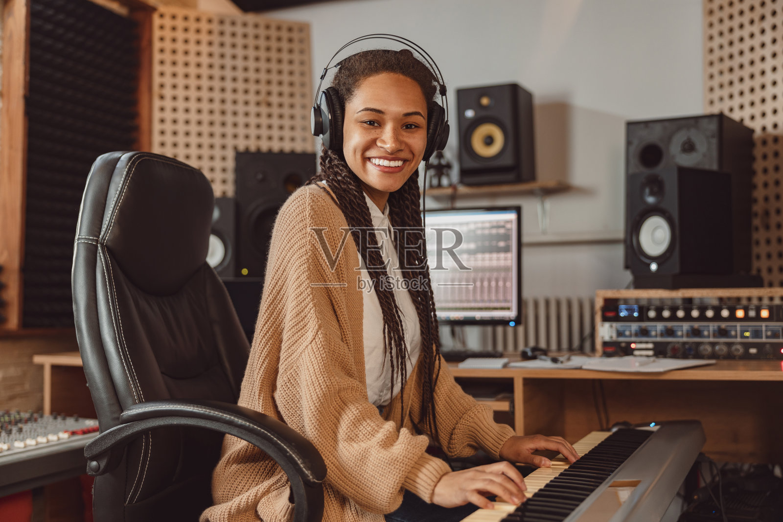 时尚漂亮的非洲女音响工程师演奏合成器和排练她的新专辑在录音室照片摄影图片