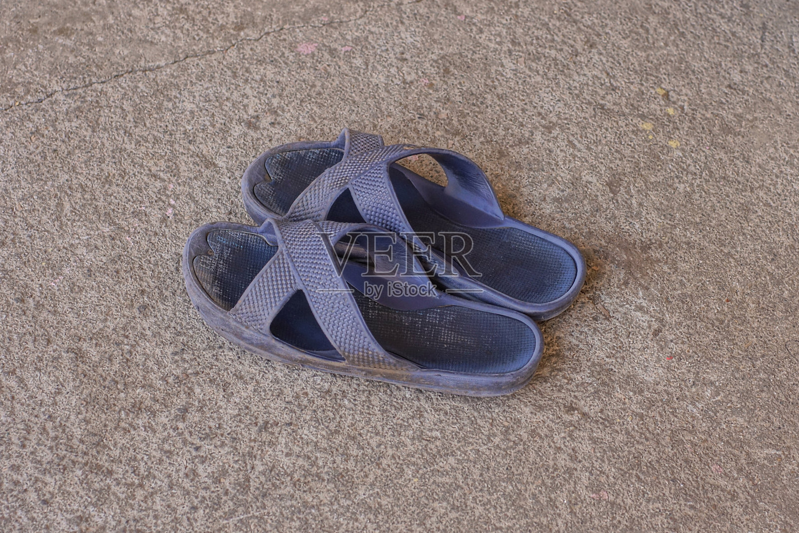 灰色的柏油路上放着两只蓝色的夏季塑料拖鞋照片摄影图片