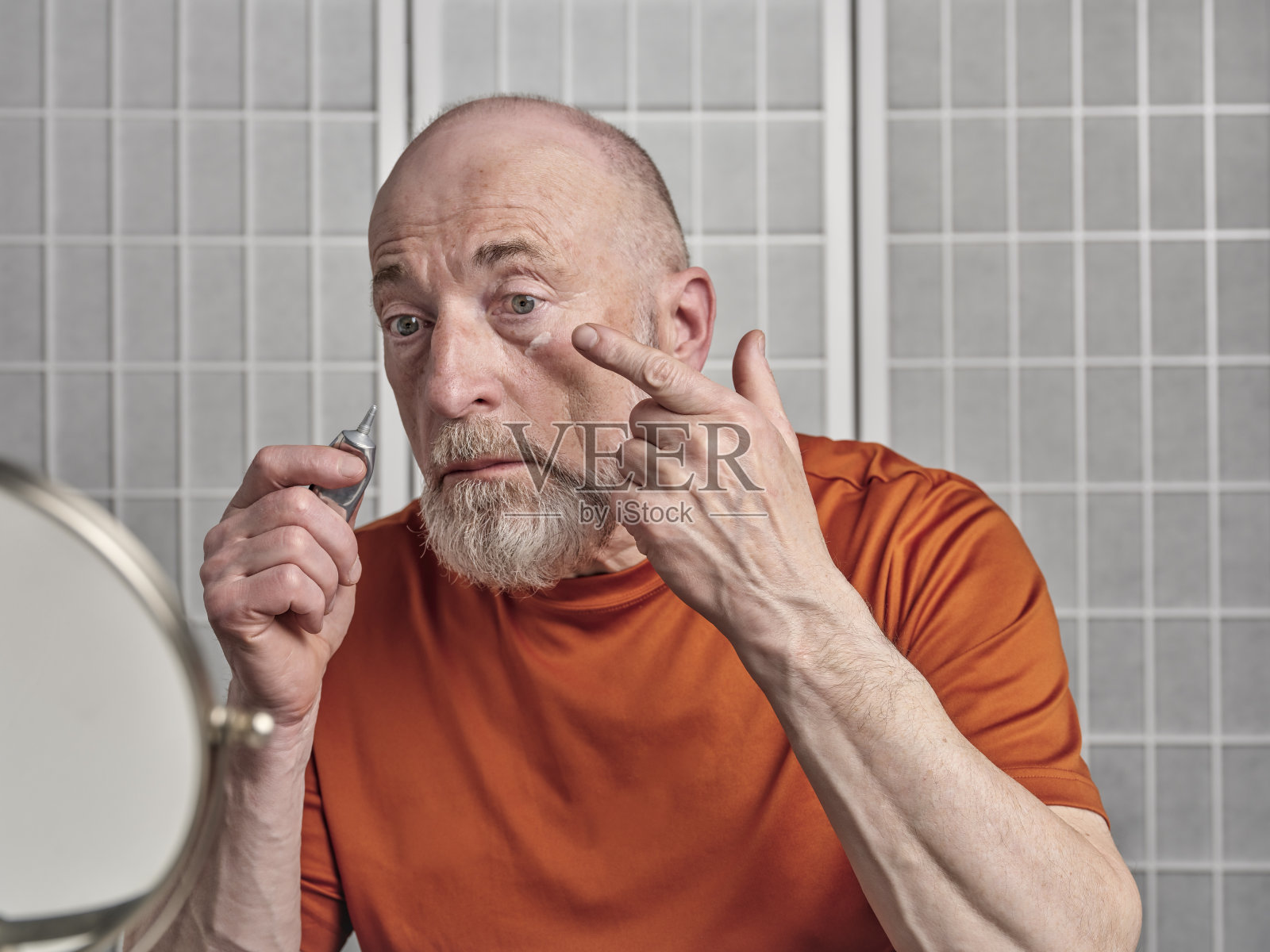 一位老人正在眼睛下面涂视黄醇乳霜照片摄影图片