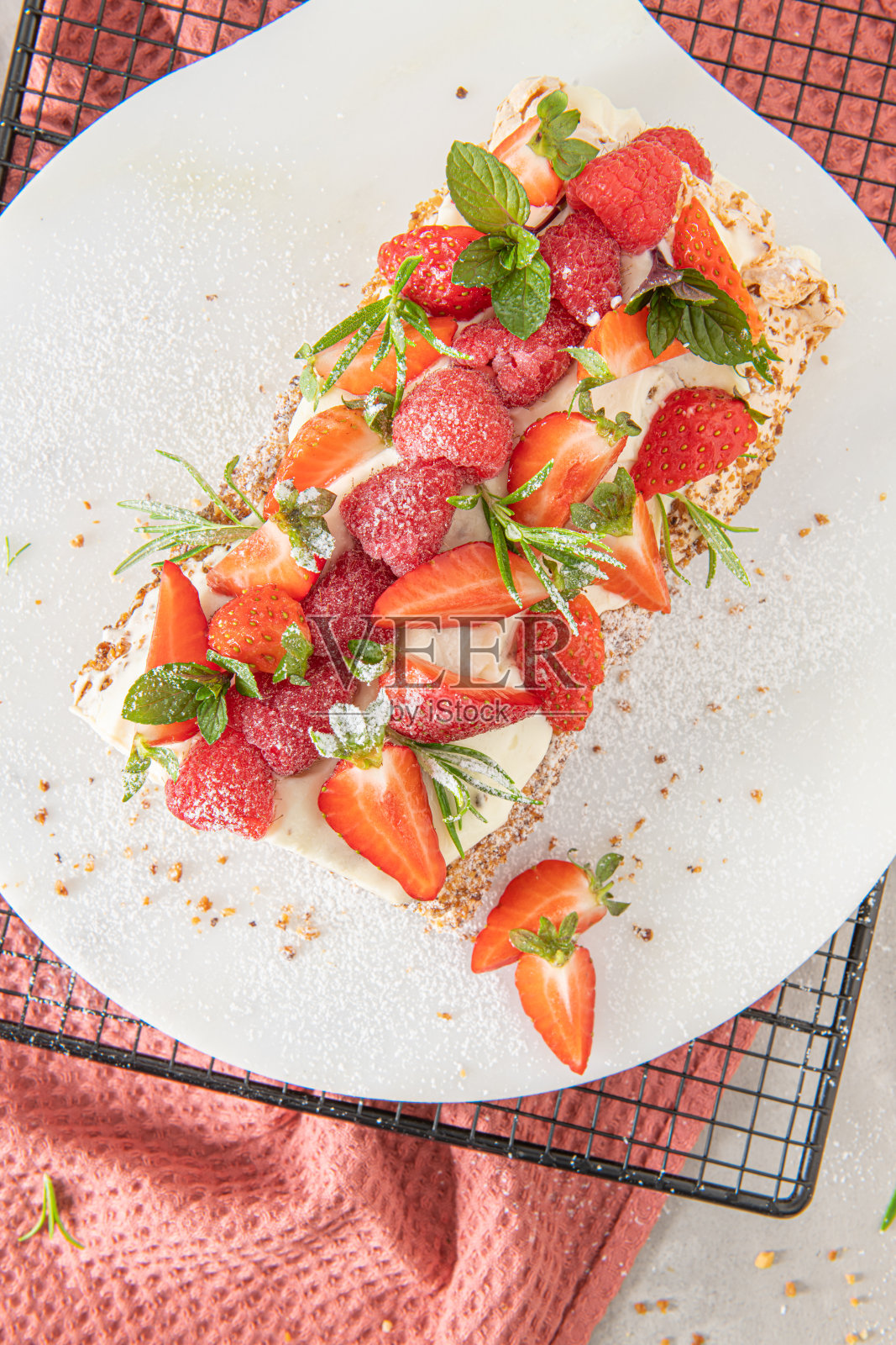 蛋白酥皮卷配上松软的奶油，松脆的花生，薄荷，迷迭香，里面填上覆盆子和草莓。巴芙洛娃夏季甜点照片摄影图片