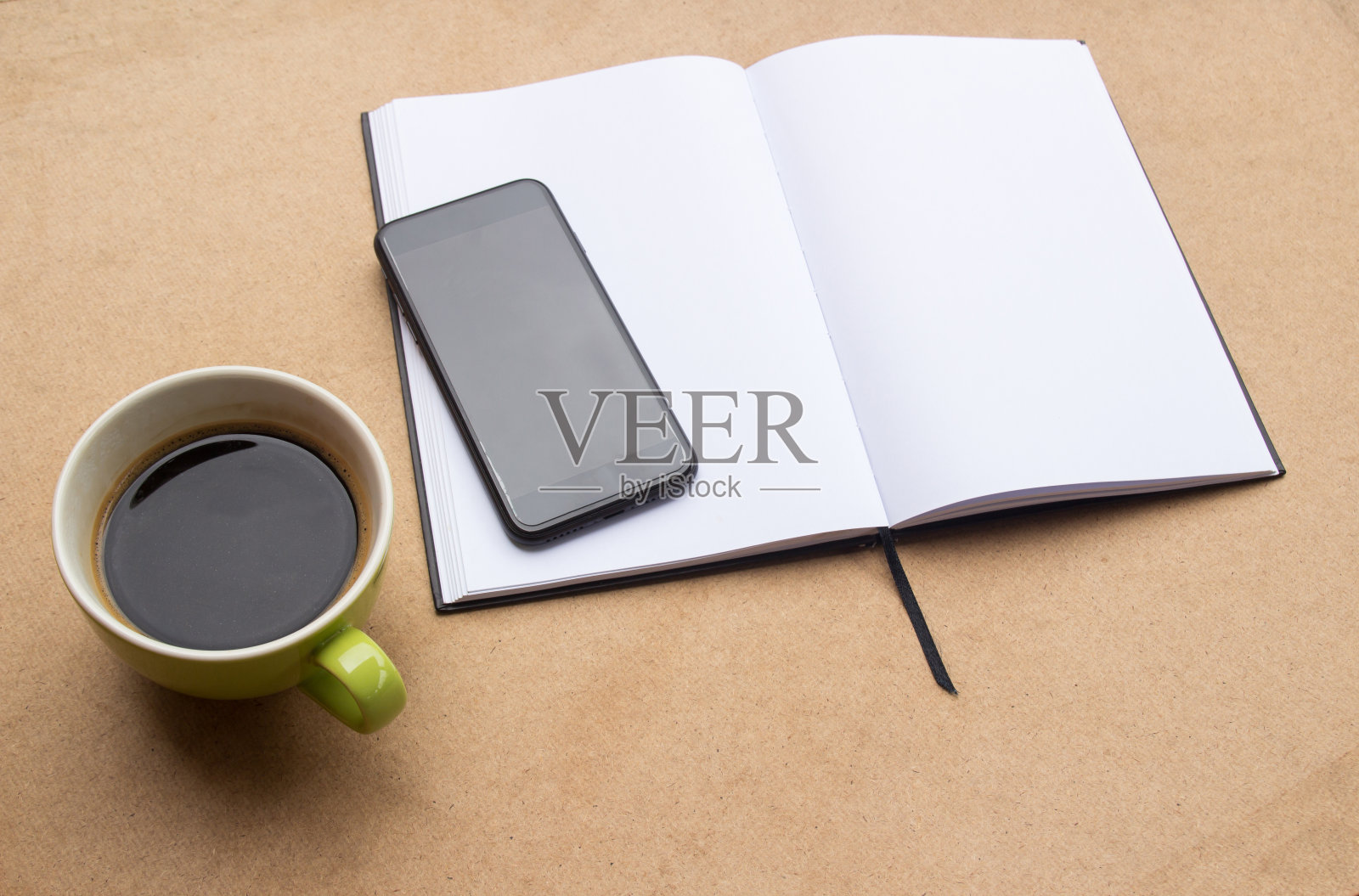 空白笔记本和咖啡与智能手机的木桌背景。照片摄影图片