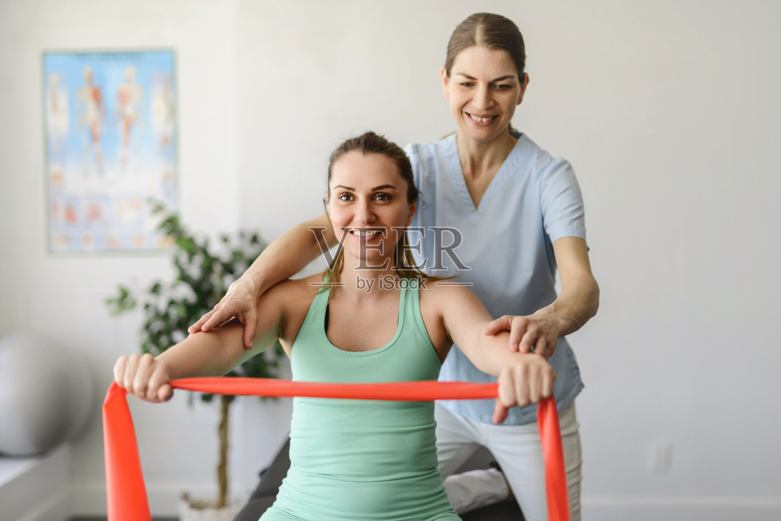 现代康复理疗女工作者与女病人使用弹性材料照片摄影图片
