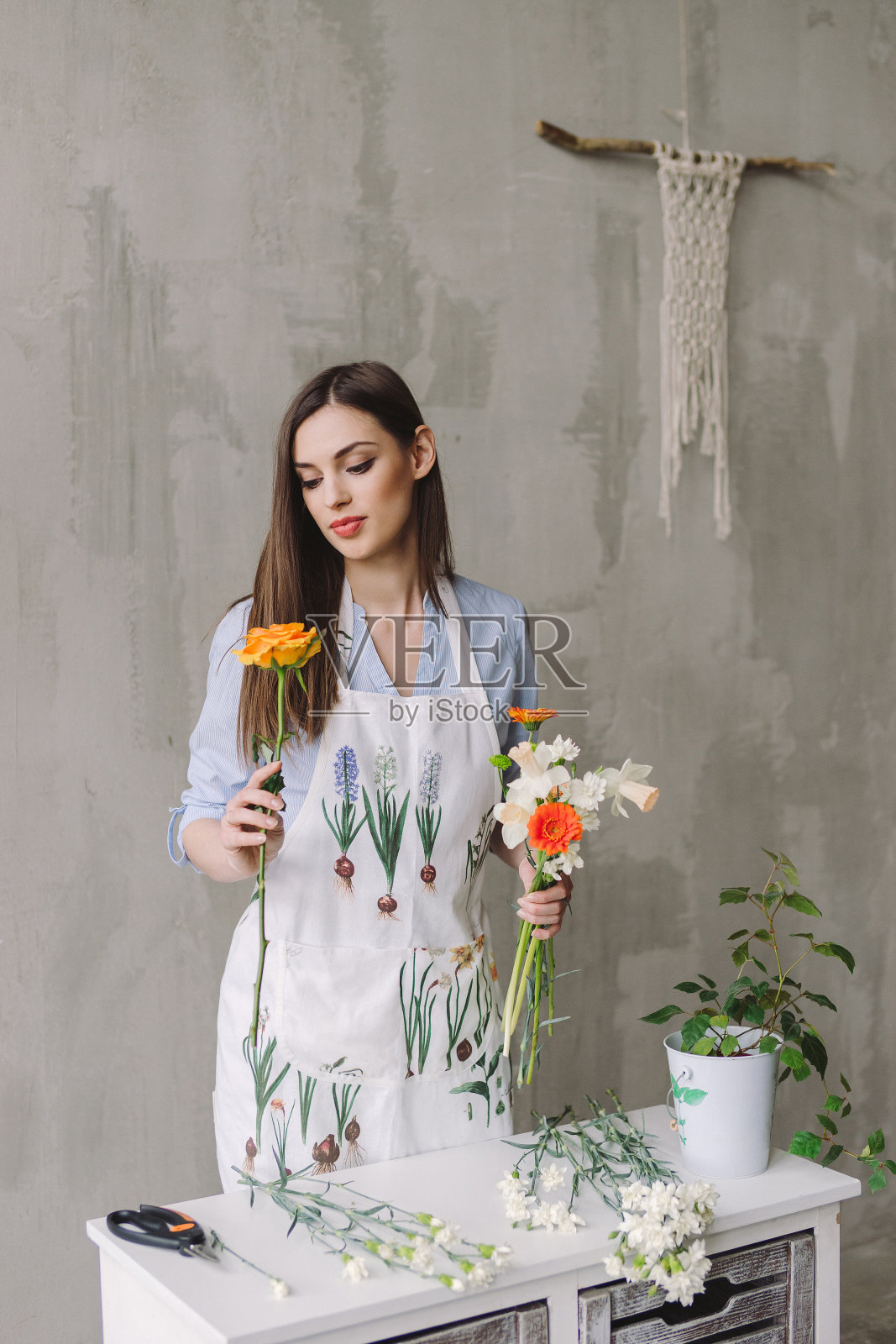 花店的工作空间:年轻漂亮的白人妇女制作花卉装饰品，一束花在她的手中。照片摄影图片