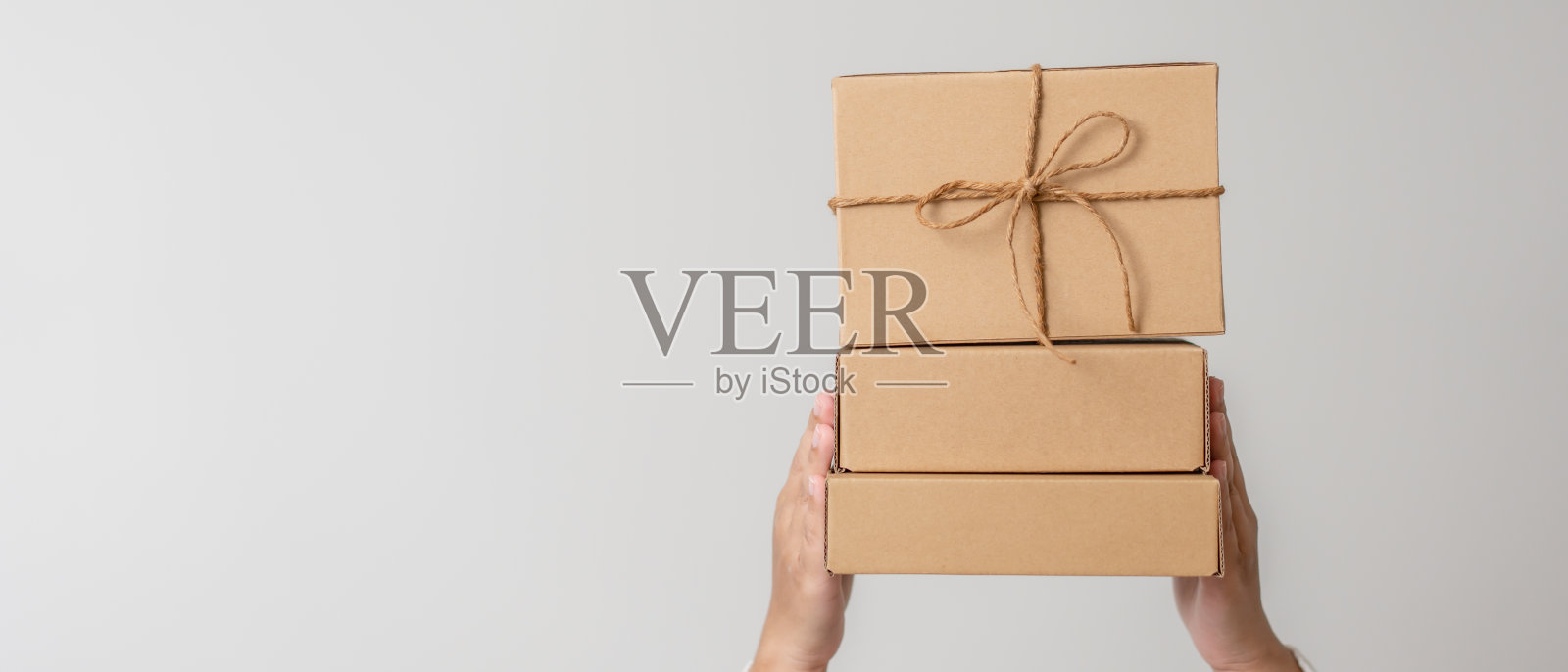 女人手捧系着丝带蝴蝶结的礼品盒。极简主义礼品盒概念照片摄影图片