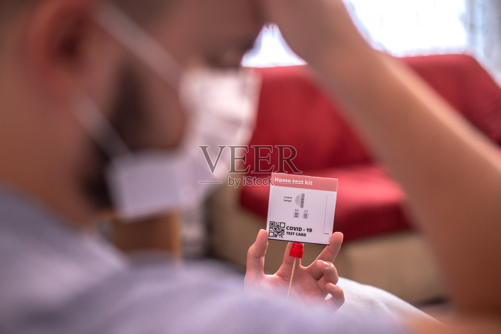 一名年轻男子在家中使用抗原试剂盒进行新冠病毒自我检测照片摄影图片