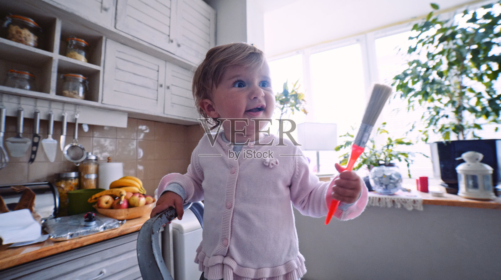 宝宝在厨房的梯子上玩油漆刷。照片摄影图片