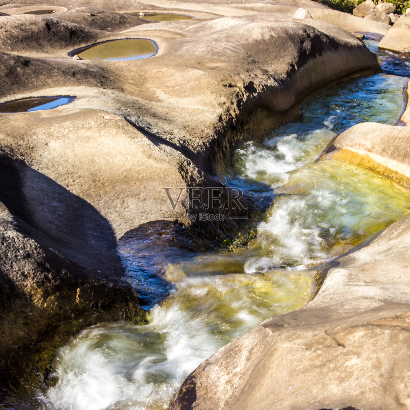 在德拉肯斯堡山脉中，一条蜿蜒的山涧流过一块光滑的岩石。照片摄影图片