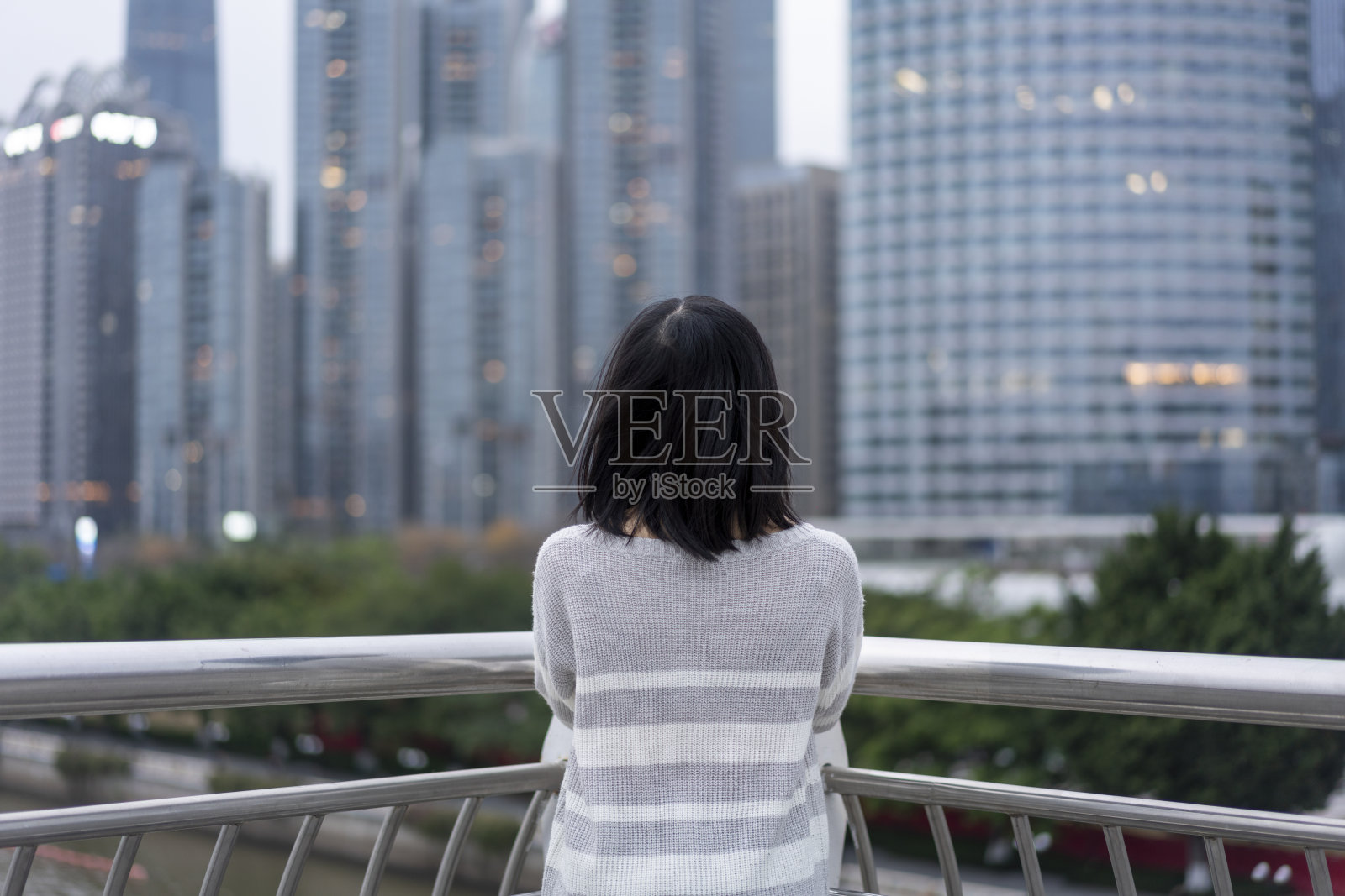 在市中心的一座桥上，一位亚洲妇女望着远方照片摄影图片