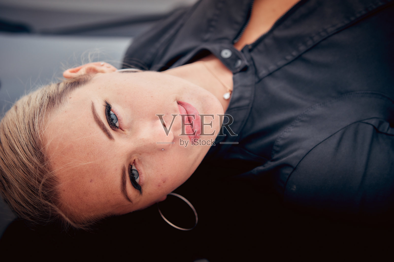 一个金发女人躺在汽车引擎盖上，是一个中年女人的肖像照片摄影图片