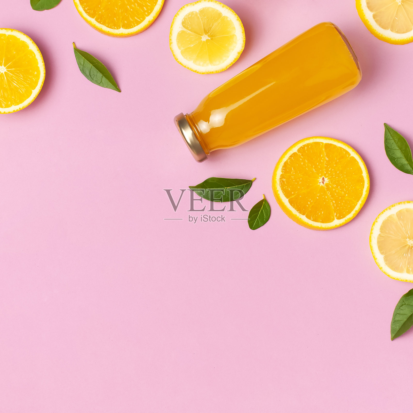 平面布局的构成与玻璃瓶的果汁或新鲜，切片新鲜柠檬和橙，绿色的叶子，鸡尾酒管在粉红色的背景俯视拷贝空间。柑桔汁维他命C概念水果照片摄影图片