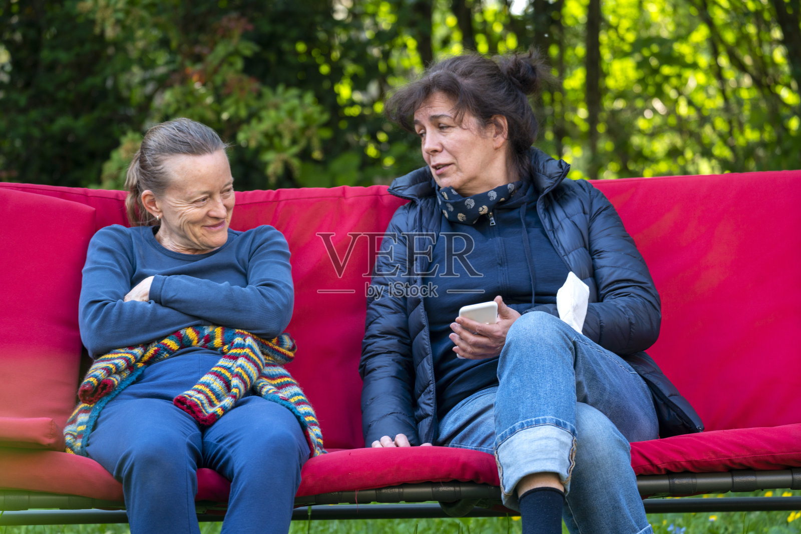 两个成熟的女人坐在花园里讨论照片摄影图片