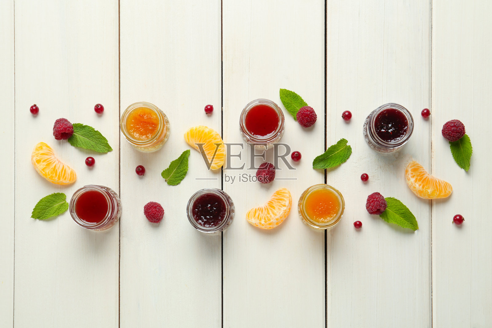白色木桌上平铺着装满不同果酱和新鲜食材的罐子照片摄影图片