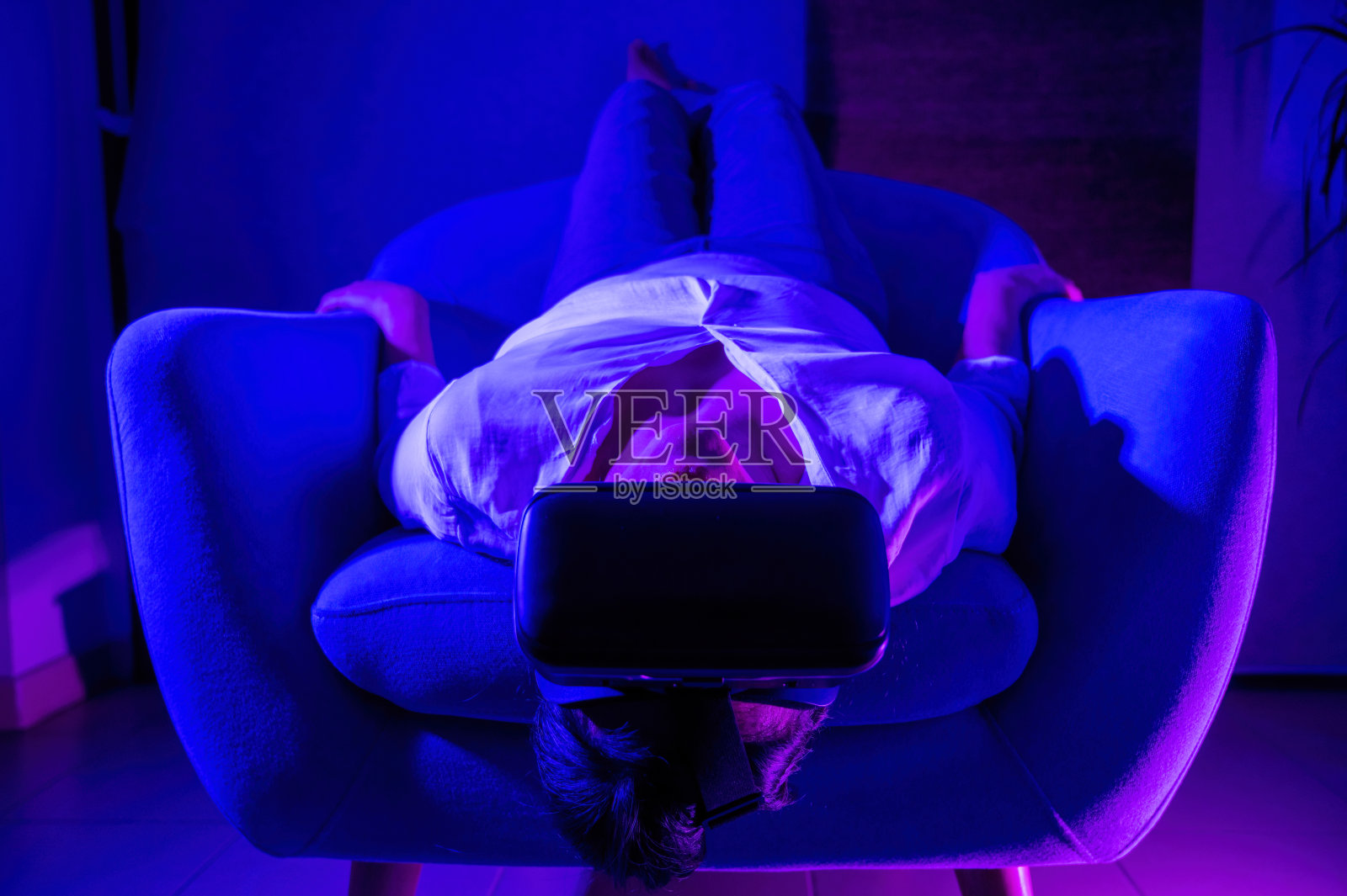 放松的女人坐在扶手椅上倒置与增强现实眼镜照片摄影图片