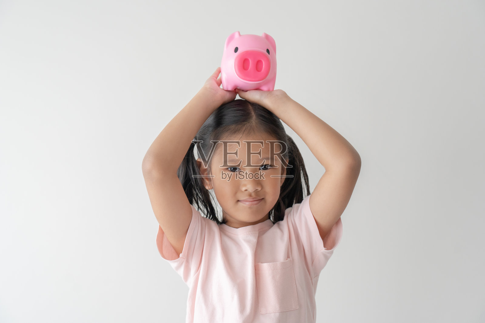 孩子抱着她的粉红存钱罐的想法，为未来或教育储蓄。照片摄影图片