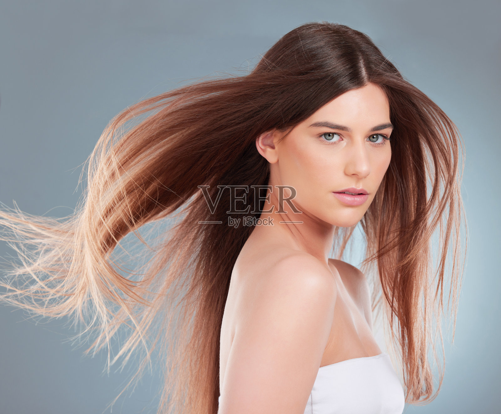 摄影棚拍摄的一个美丽的年轻女子炫耀她的棕色长发照片摄影图片