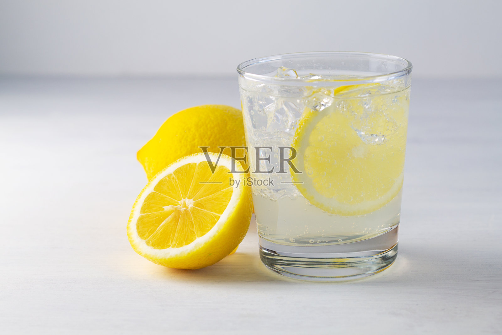 柠檬在玻璃。夏季清爽鸡尾酒，白色木制背景上的酸橙。新鲜的夏日冰柠檬水加黄色柑橘。本空间照片摄影图片