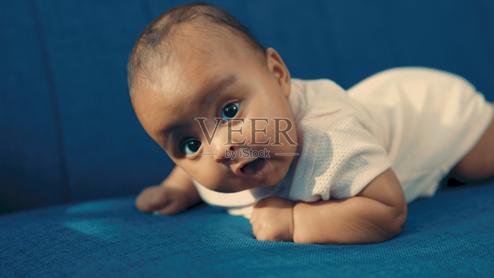 黑孩子躺在蓝色的沙发上照片摄影图片