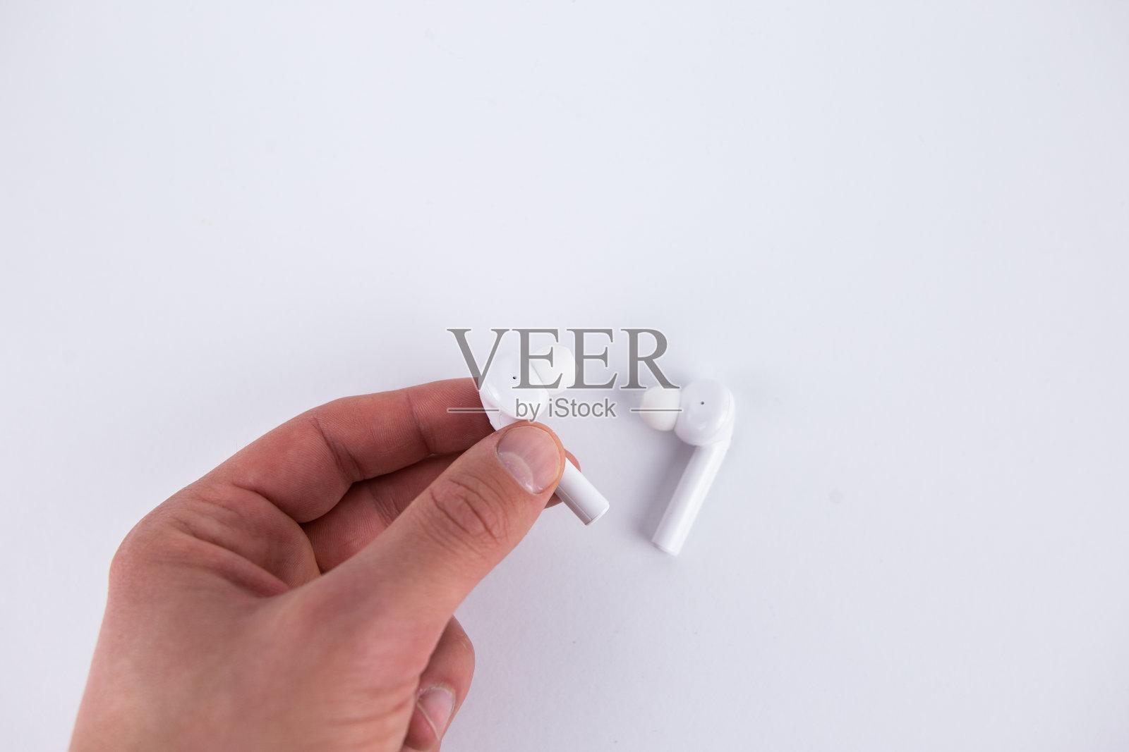 白色的无线耳机在手中的白色背景隔离照片摄影图片