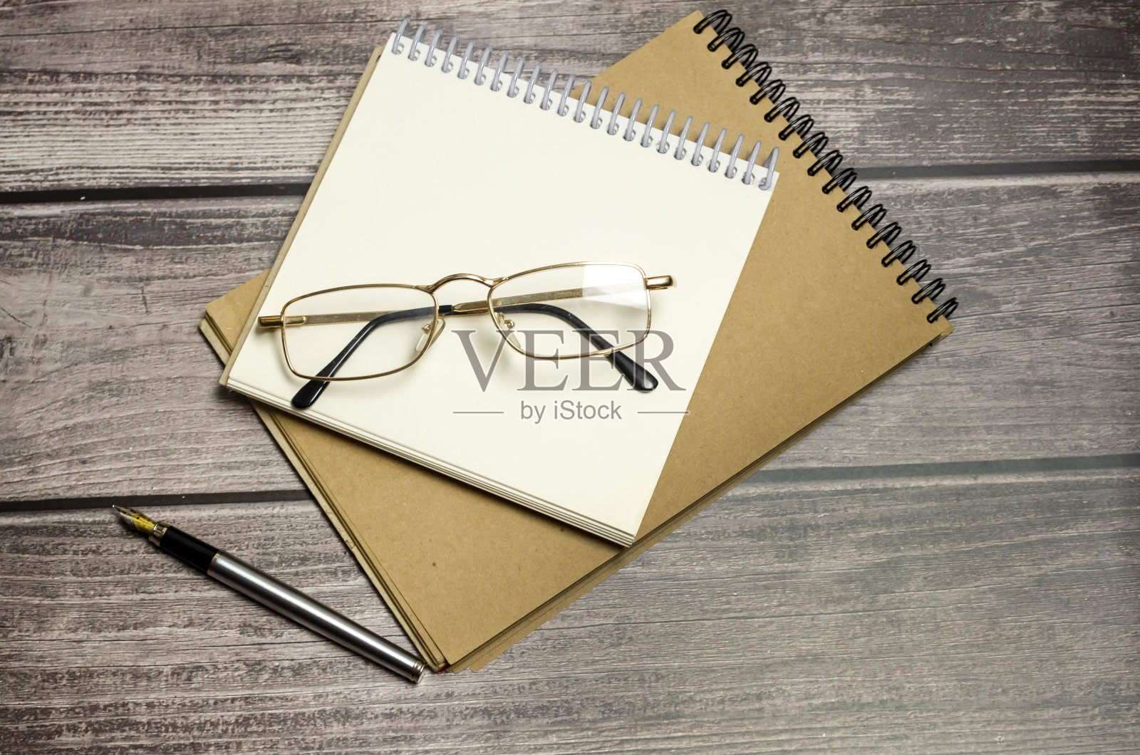 木桌上放着眼镜、笔和记事本照片摄影图片