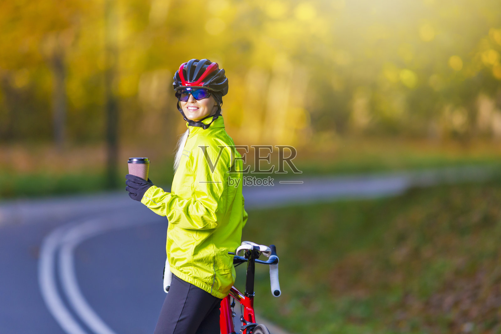 专业的公路自行车赛。高加索女性自行车手与道路自行车在户外对秋天的背景。照片摄影图片
