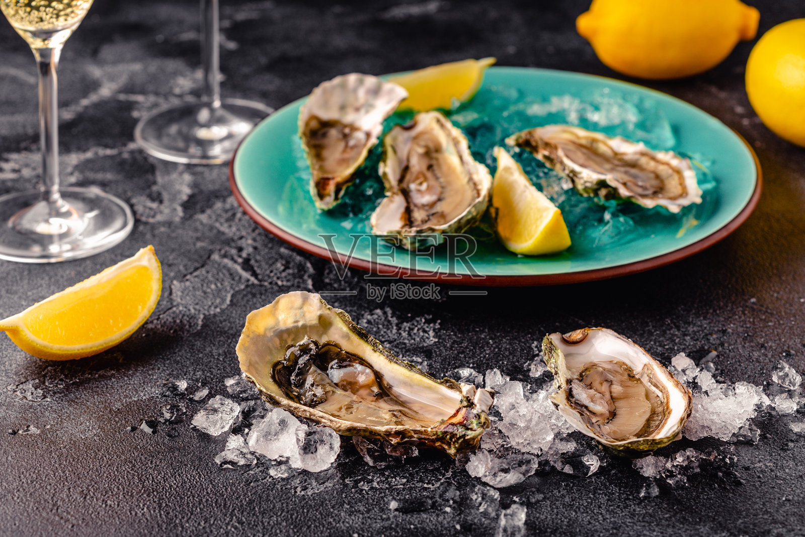 在深色的桌子上打开新鲜的牡蛎，配上柠檬和冰块。照片摄影图片