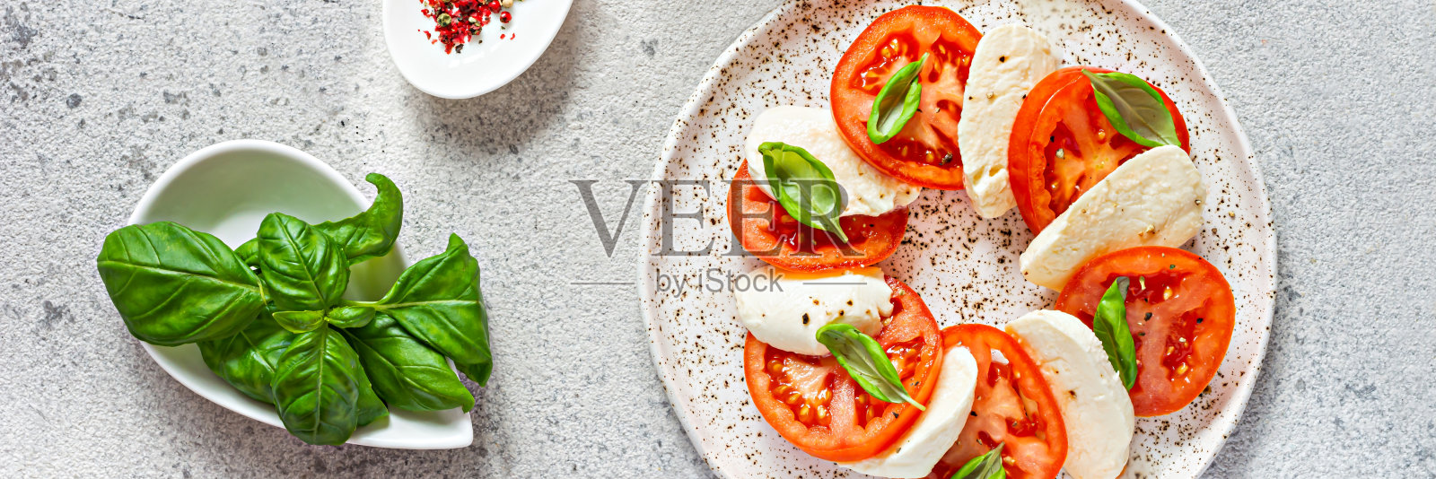 卡普里沙拉配上多汁的西红柿，新鲜的马苏里拉奶酪和香蒜沙司。一个美味和健康的开胃菜的概念，平铺。照片摄影图片