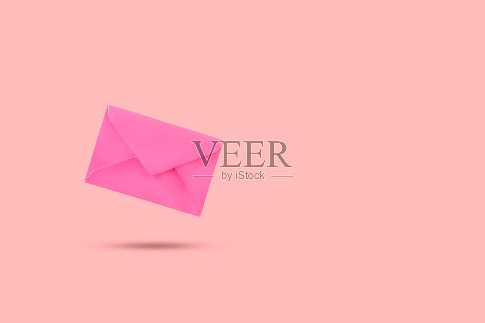 粉色背景上漂浮着一个粉色信封照片摄影图片