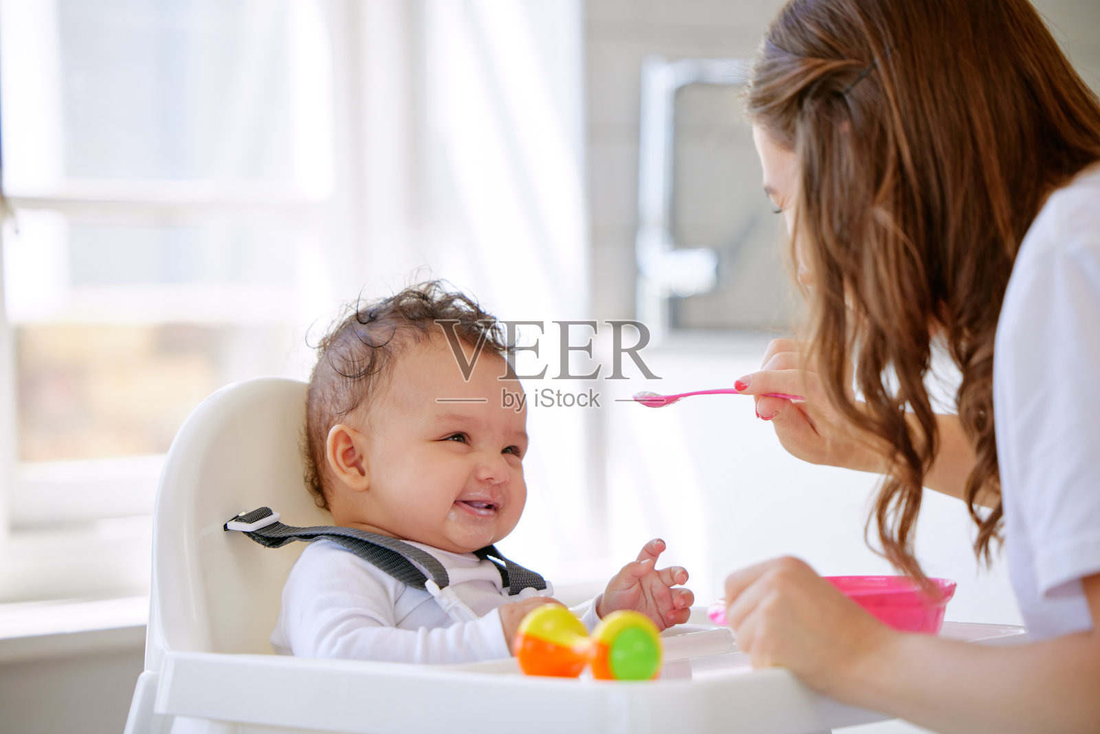 年轻母亲在厨房喂女儿照片摄影图片