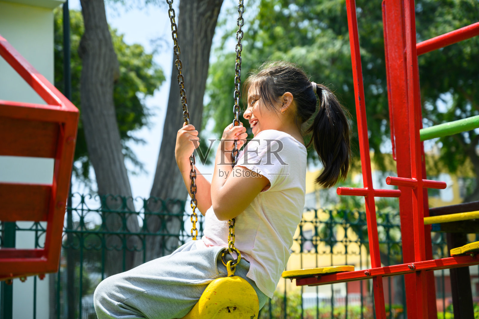 快乐的小西班牙女孩在夏天的时候在公园里玩的开心的微笑和健康的笑，可爱的女孩在夏天的秋千上玩的开心。快乐的度假生活理念。照片摄影图片