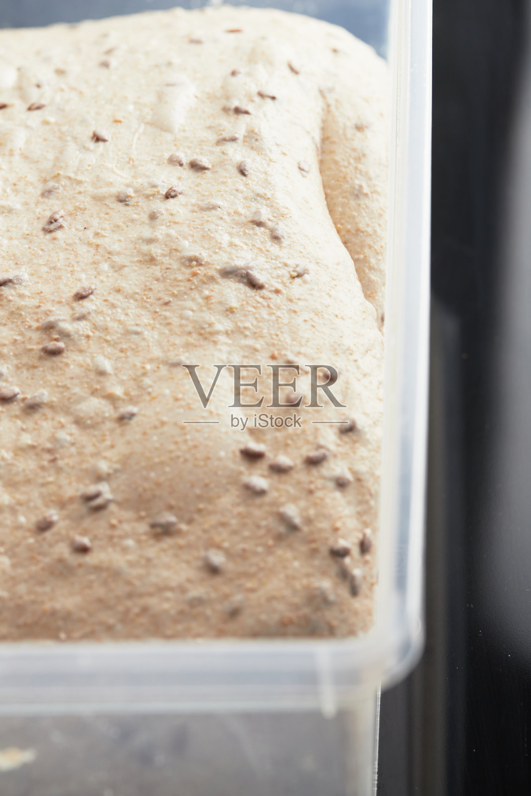 面团在容器中。亚麻籽面包。含谷物的健康全麦面包的概念。照片摄影图片