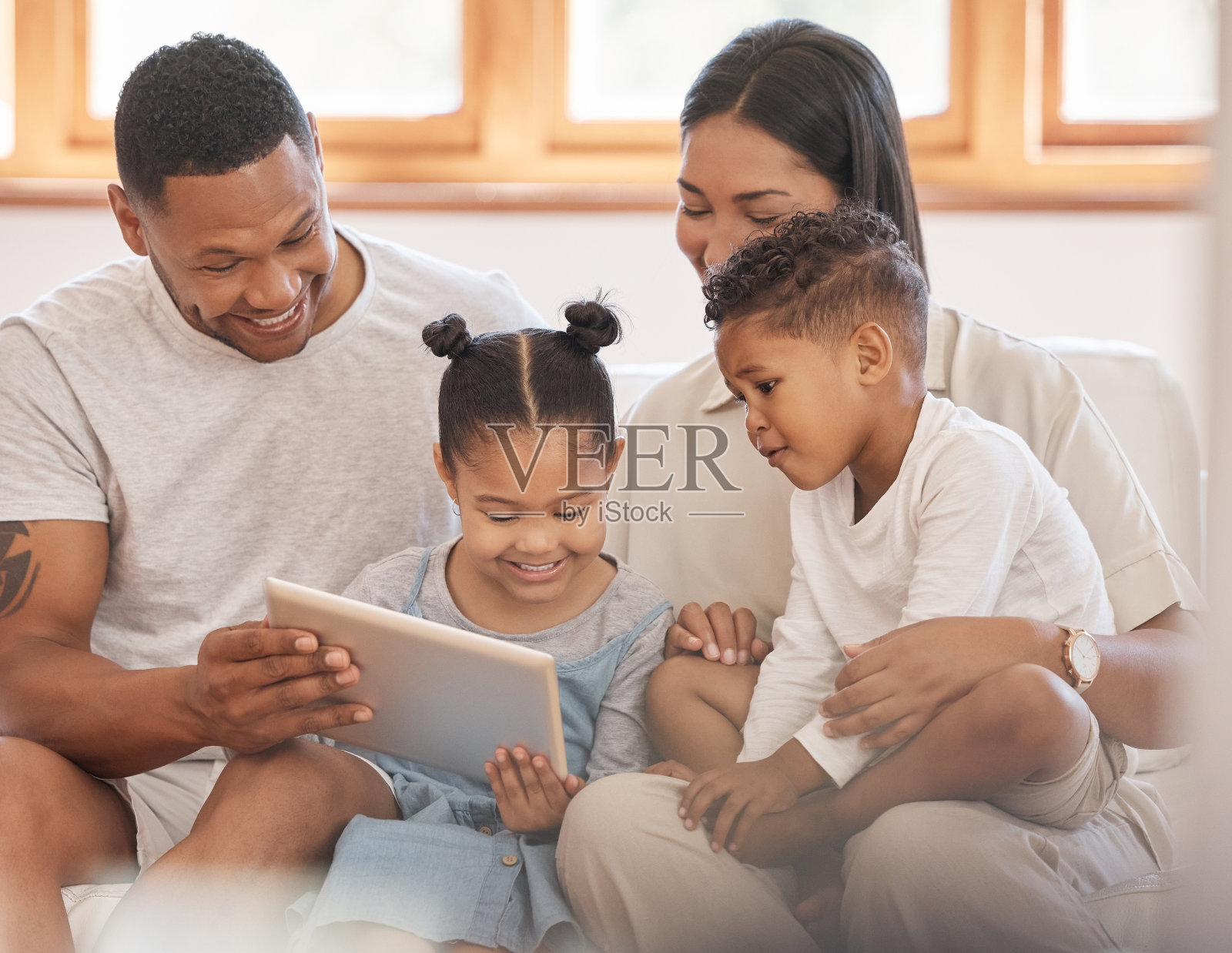 快乐的混血四口之家在沙发上通过平板电脑观看网络电影照片摄影图片