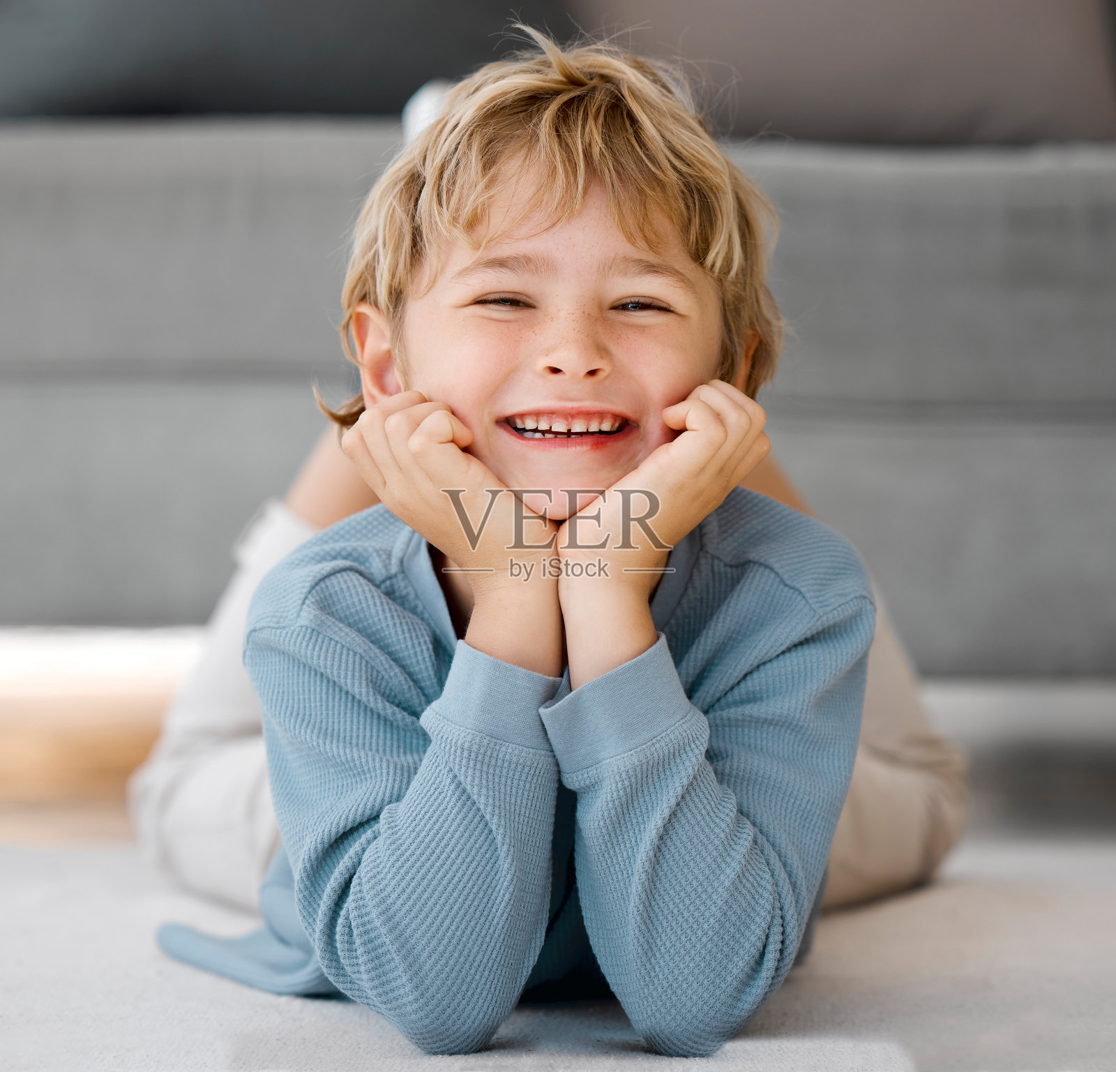 肖像快乐的孩子看着相机微笑的脸。可爱的白人孩子躺在地板上，放松在家里。快乐的童年照片摄影图片