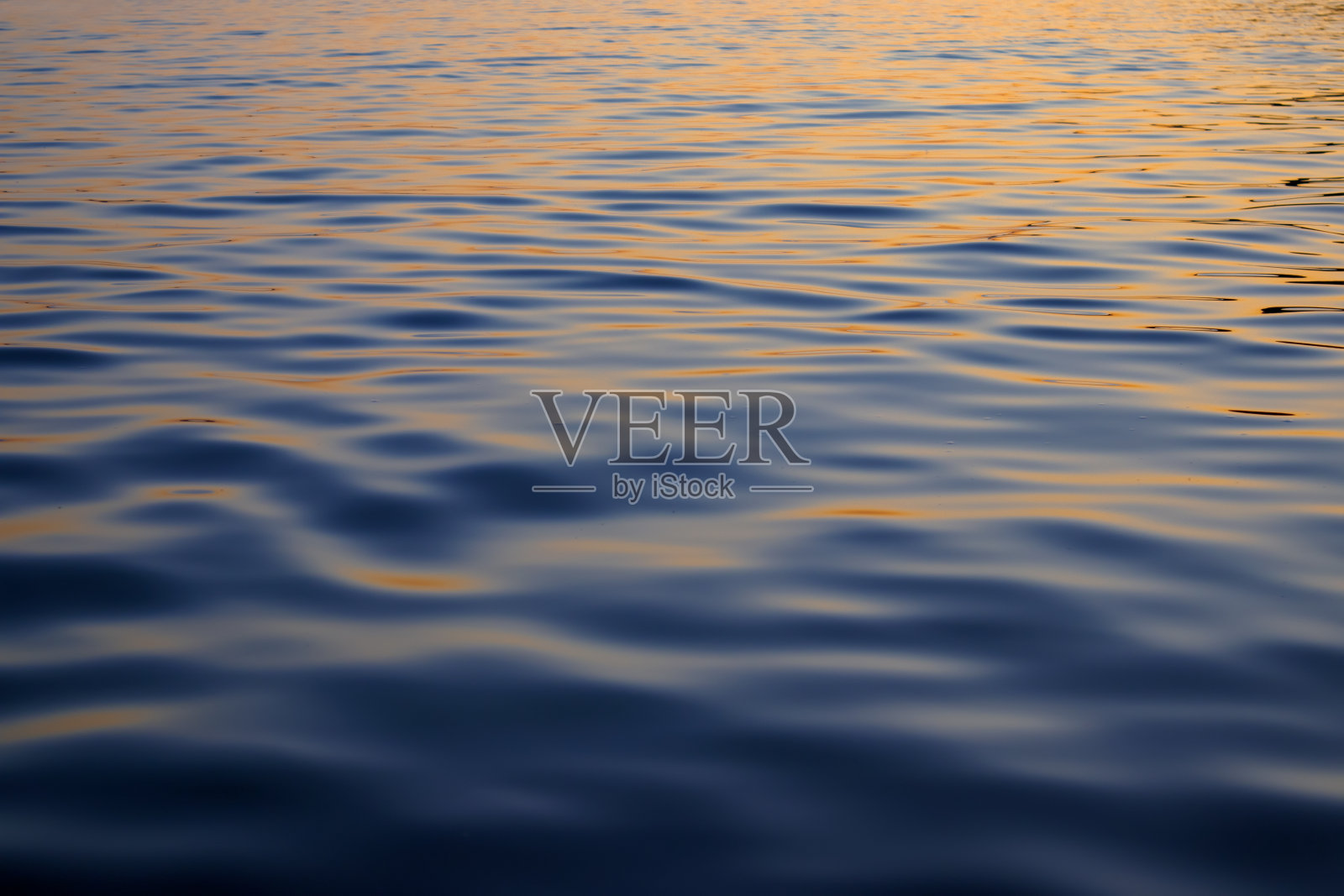 深蓝色水面与波浪和反射日落作为纹理。照片摄影图片