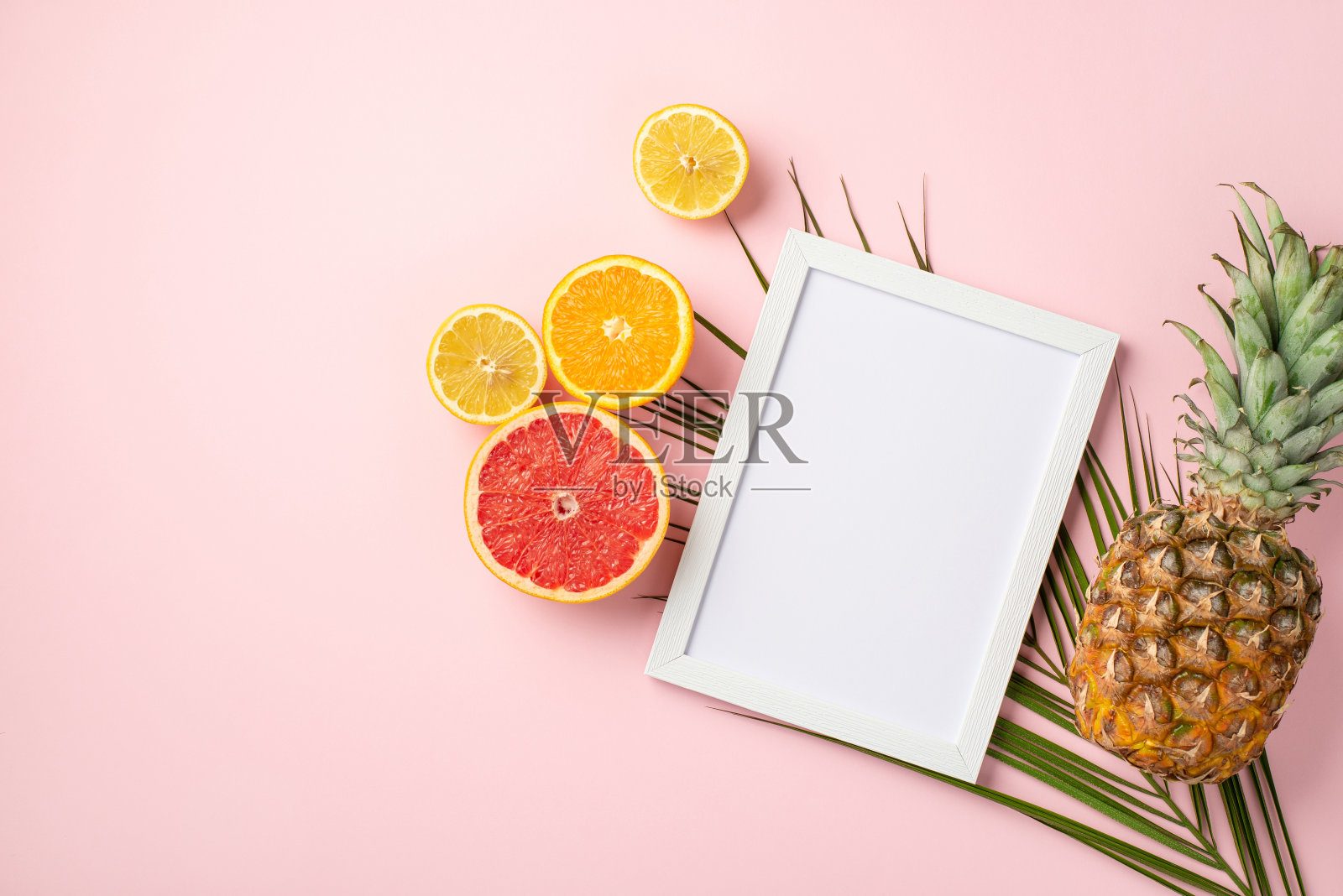 夏天休息的概念。顶视图照片的白色相框和成熟的热带水果切柠檬橙柚子菠萝和棕榈叶孤立粉彩粉红色的背景与copyspace照片摄影图片