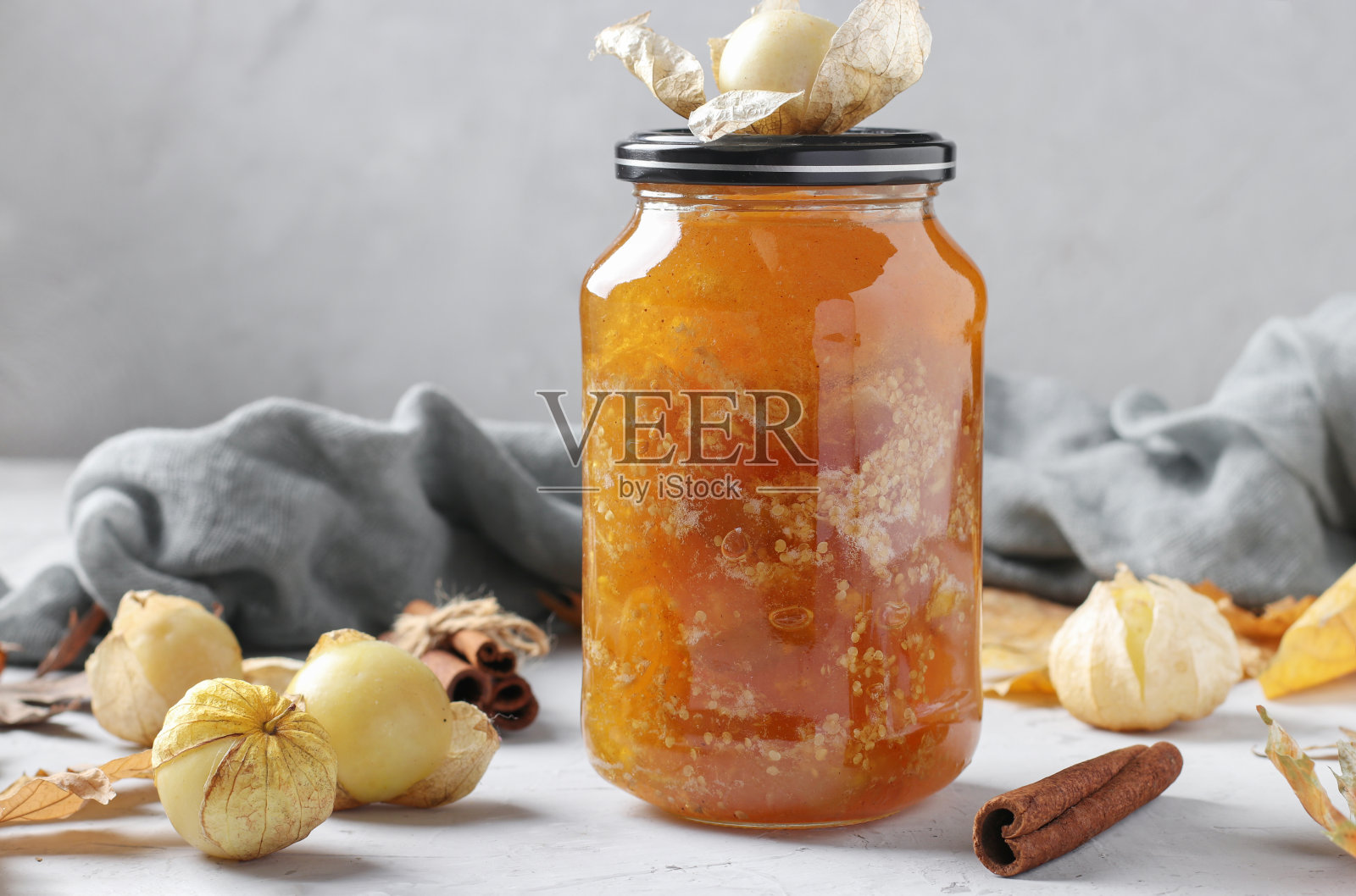自制透明酸浆果酱与肉桂在玻璃罐上的灰色背景照片摄影图片