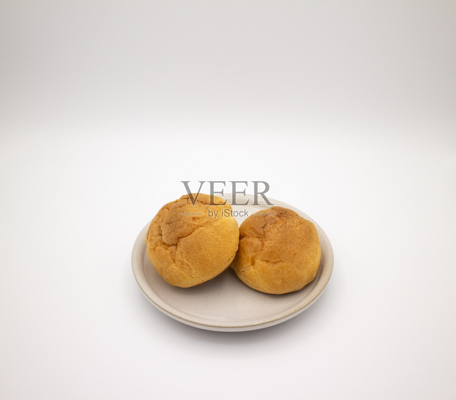 两个奶油泡芙放在白色盘子里，俯瞰着照片摄影图片