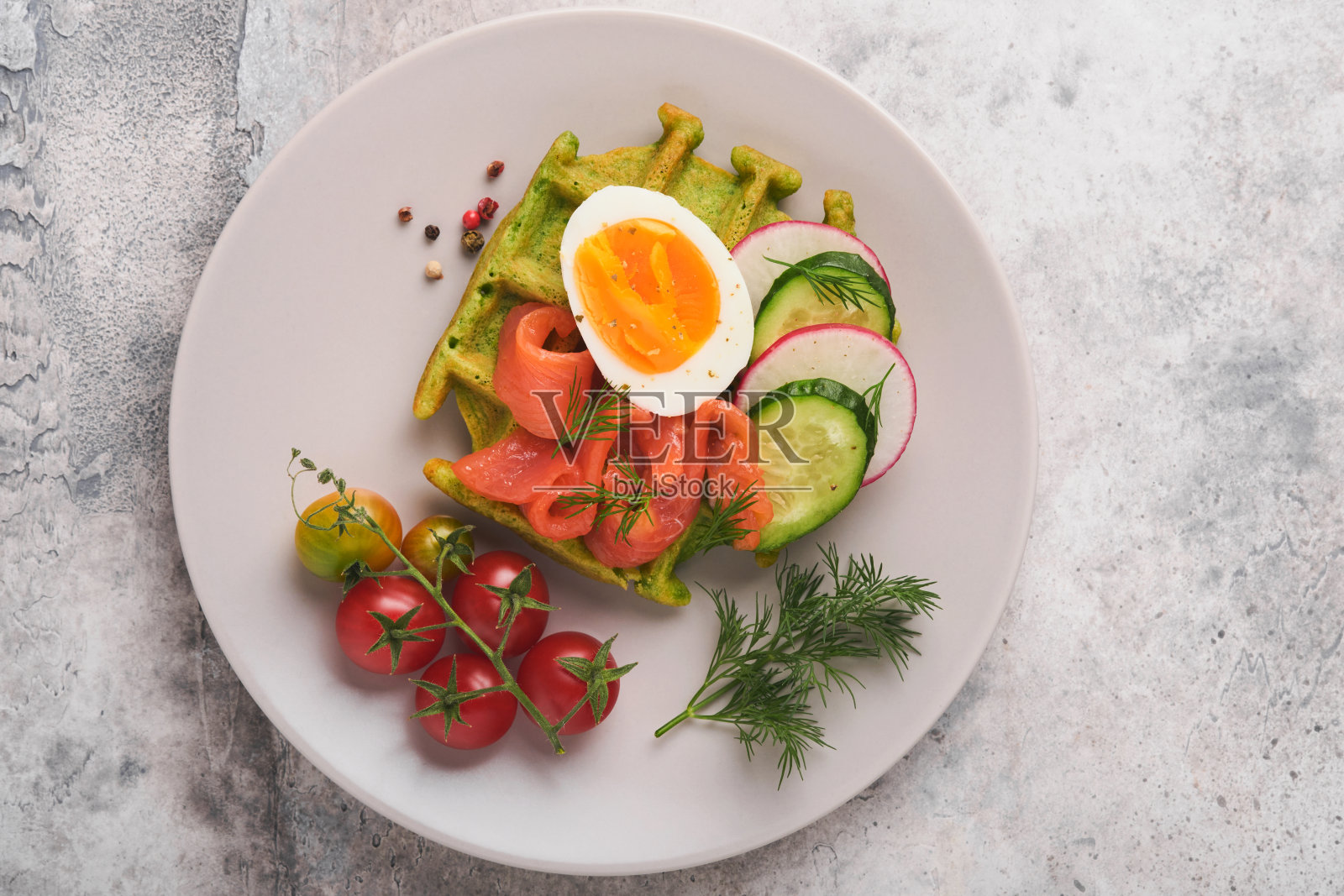 美味的华夫饼。早餐绿色华夫饼，野蒜或菠菜，鸡蛋，西红柿，三文鱼，放在灰色的混凝土桌子上。清淡的晚餐、午餐或早餐。前视图。模拟。照片摄影图片