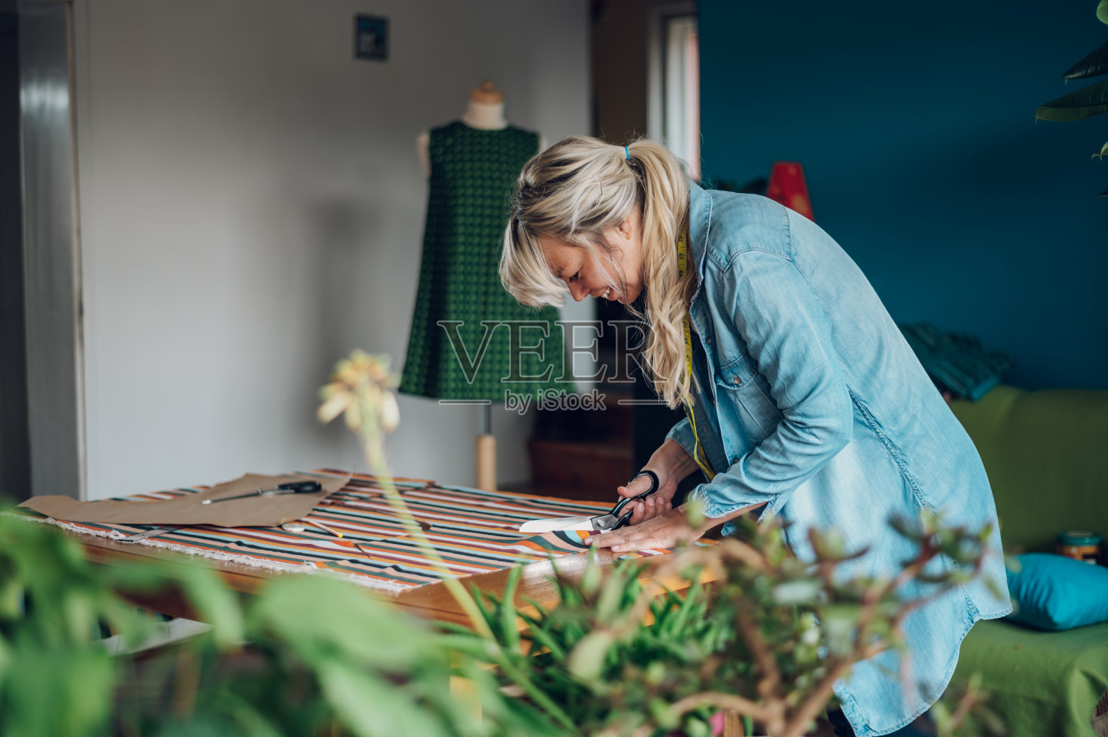 女裁缝在家工作，剪裁漂亮的衣服照片摄影图片