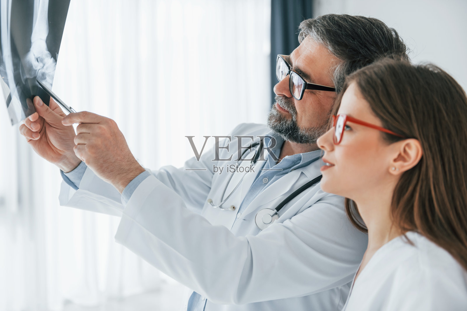 看着x射线。穿着白大褂的专业医务人员在办公室里照片摄影图片