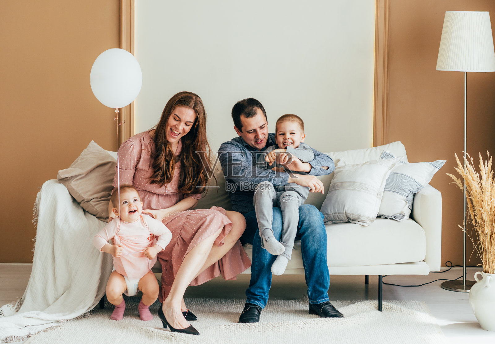 爸爸妈妈和小朋友们在客厅的沙发上无忧无虑地玩耍。照片摄影图片