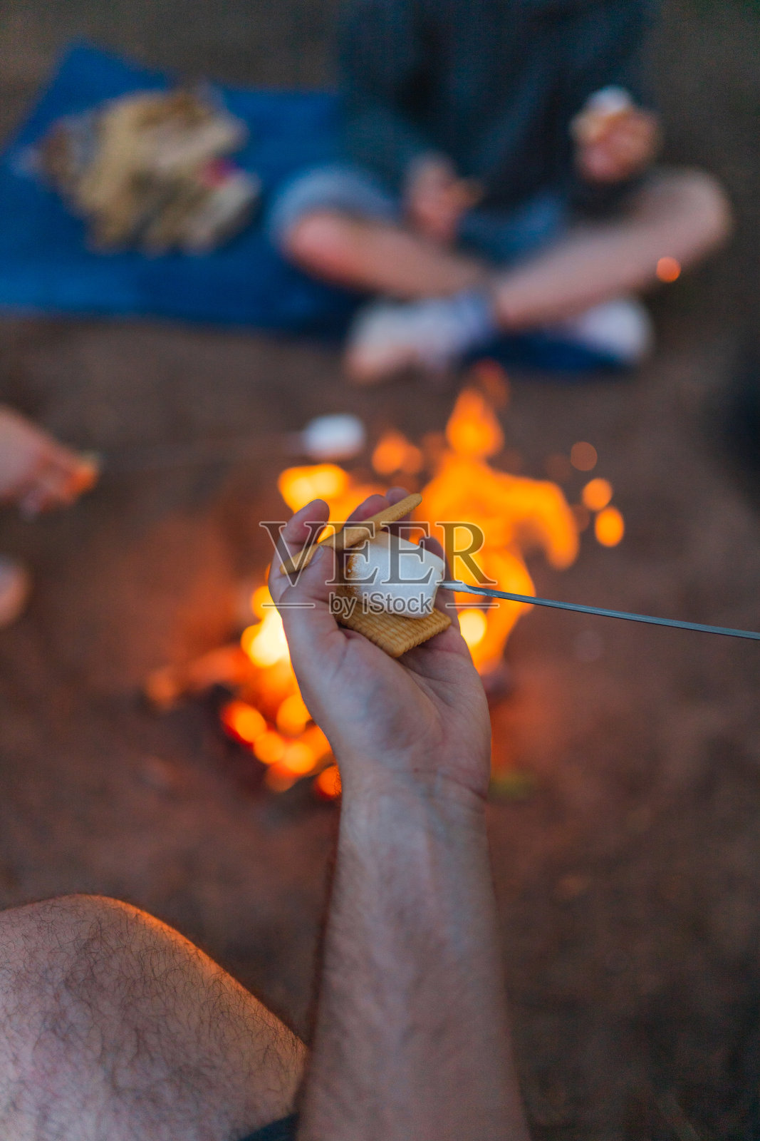 一个年轻人和朋友在户外露营时做棉花糖三明治的特写照片摄影图片
